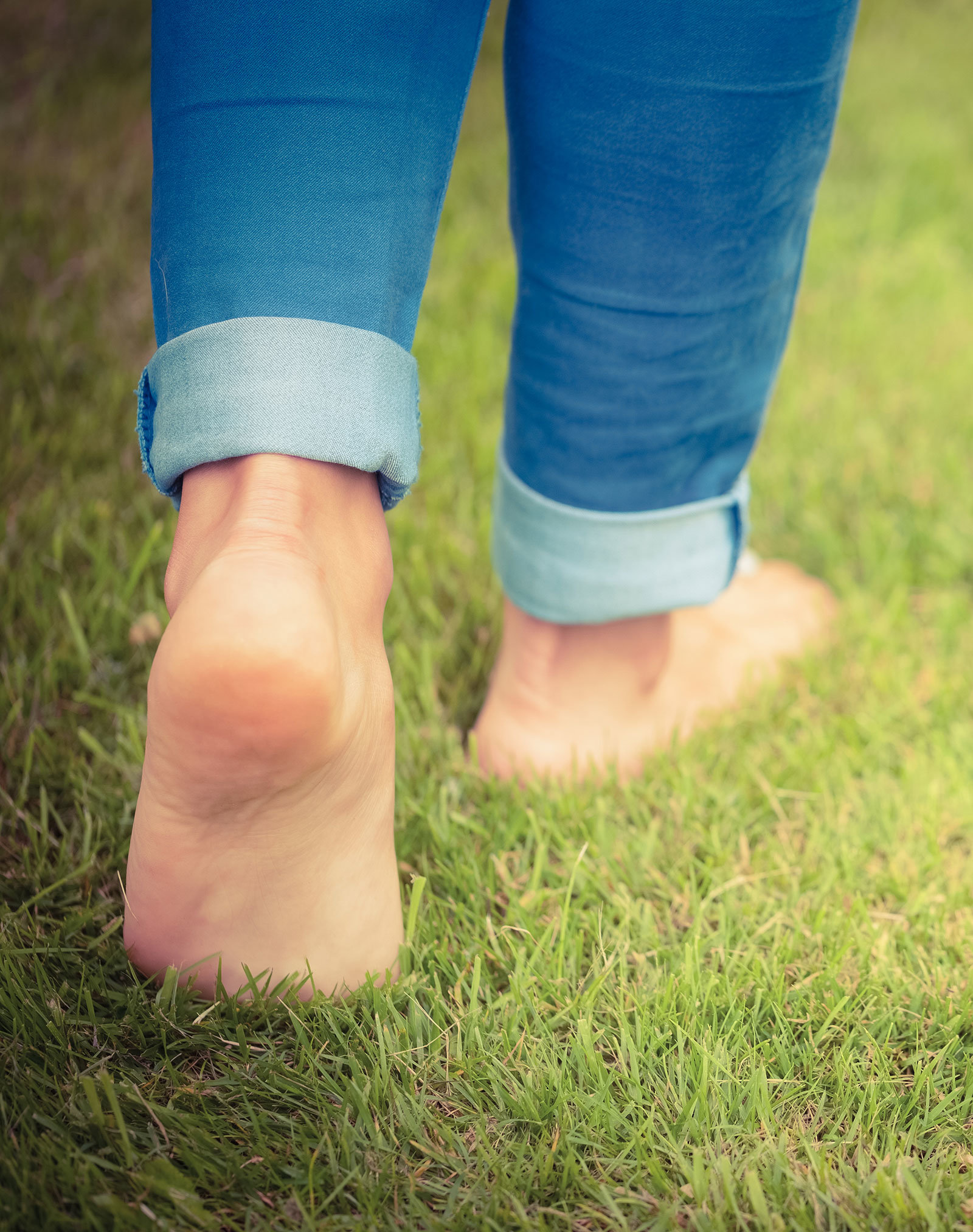 A woman's bare feet, walking on grass.