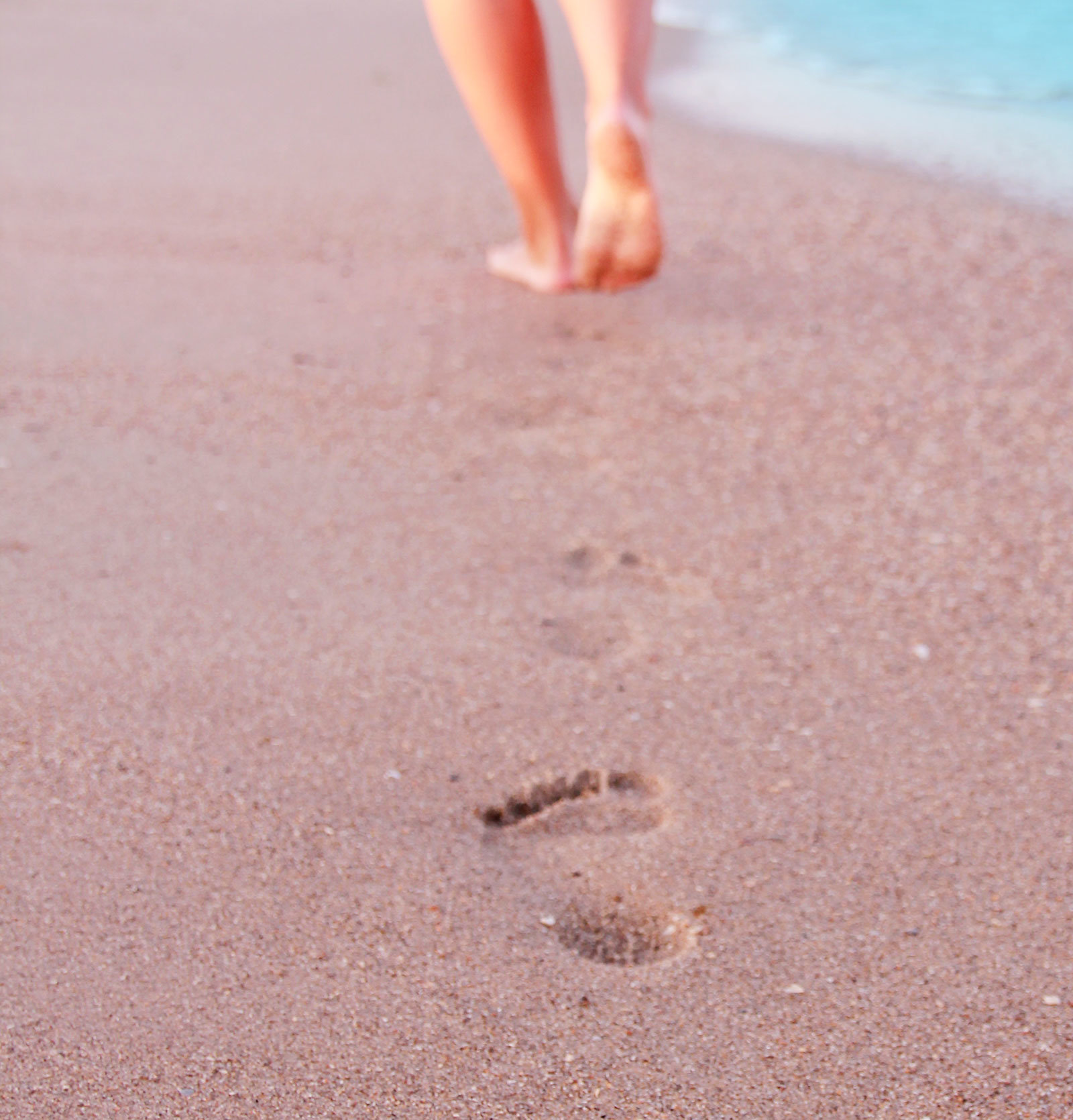 A runner at the beach and her bare foot-prints.