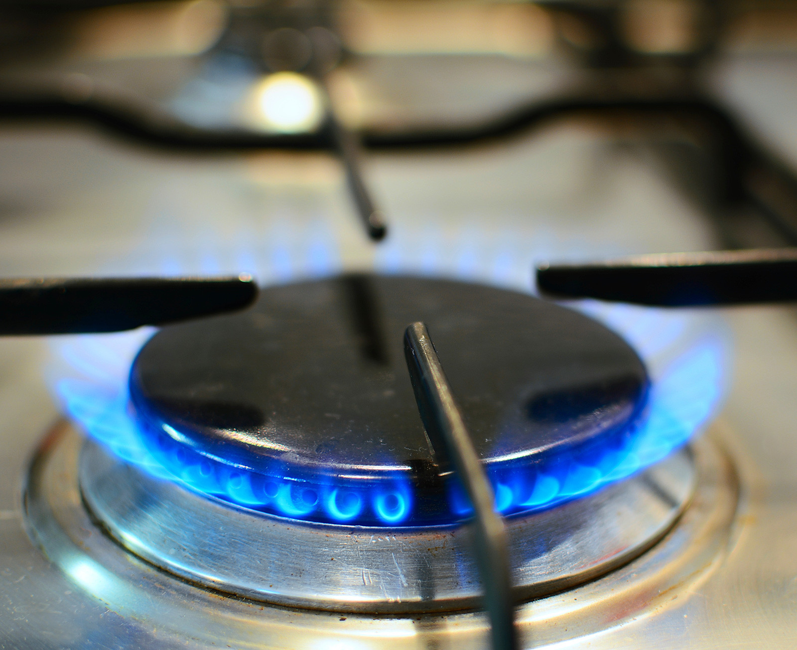 A gas stove burner turned on, creating a blue flame.