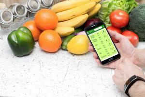 fresh fruits and vegetables with smartphone and caloria tracker