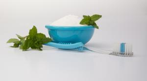 toothbrush beside blue bowl full of baking soda and topped with mint