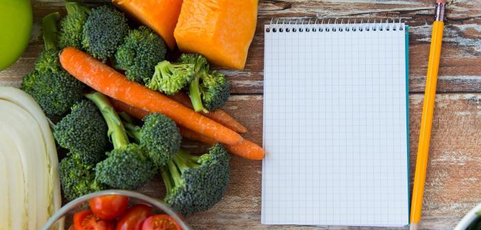 A notebook and a pencil surrounded by real food