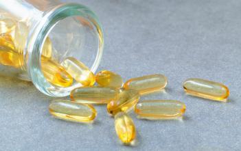 cod liver oil capsules tumbling out of a glass jar