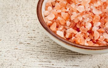 Himalayan salt crystals in a ceramic bowl on a board